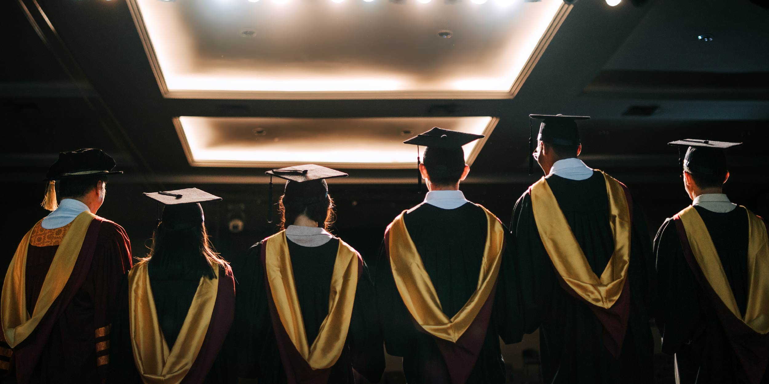 A group of students in graduation cap and gowns standing the stage