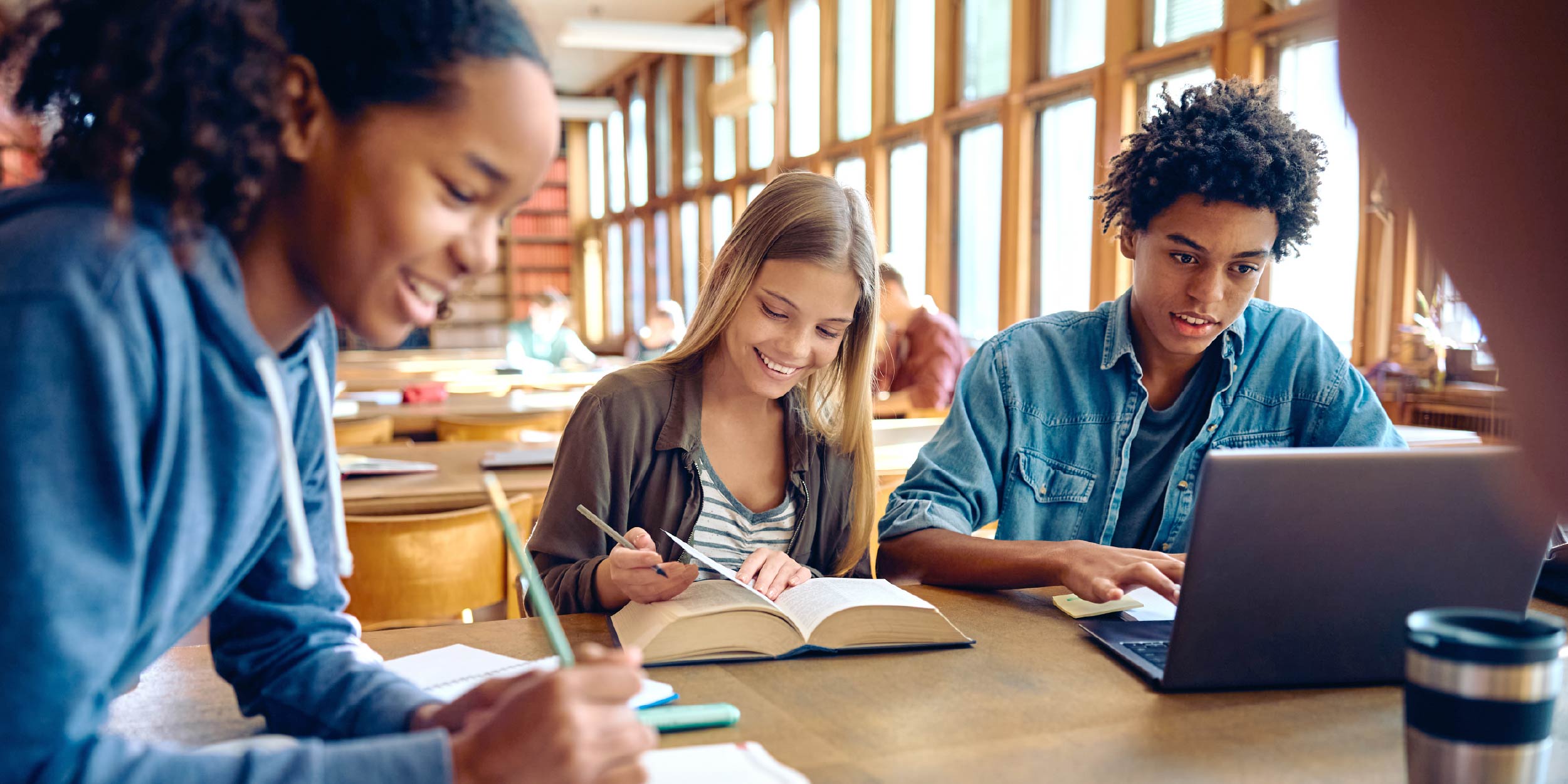 A group of students sitting at a table reading and writing