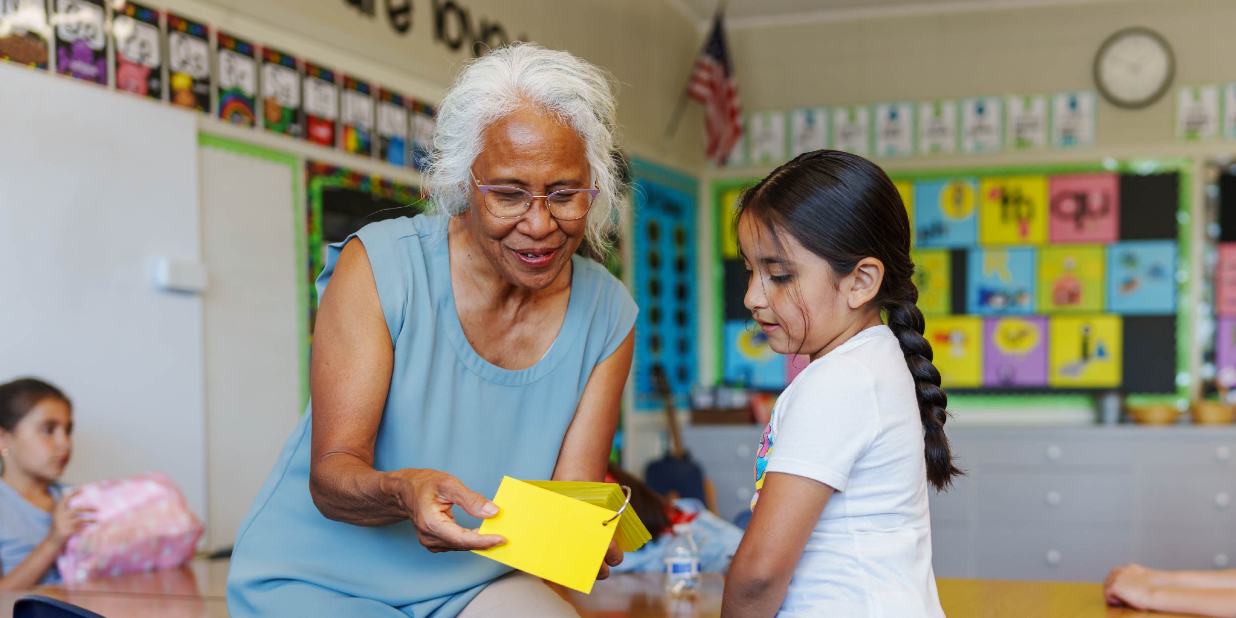A teacher and student in a classroom looking at flashcards