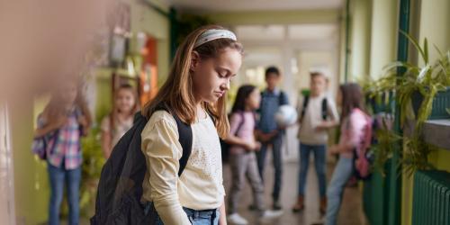 A student standing in the hallway looking upset